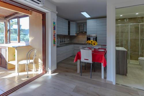 cocina y comedor con mesa roja y sillas en Portisco Living en Marina di Portisco