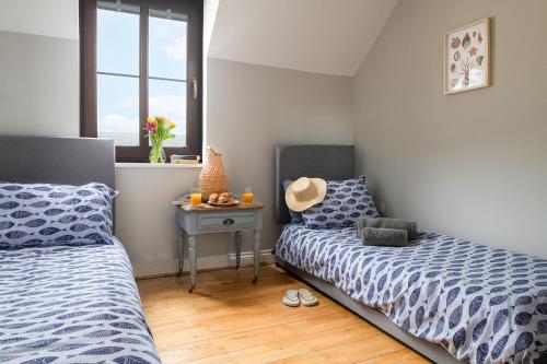 a bedroom with two beds and a table with a window at The Lookout, Burry Port in Burry Port