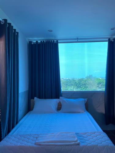 Bett in einem Zimmer mit einem großen Fenster in der Unterkunft homestay 252 Long Hải in Ấp Lò Vôi