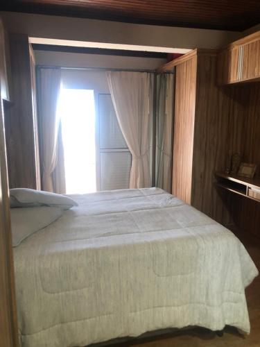 um quarto com uma cama grande e uma janela em Casa do Vale em Serra Negra
