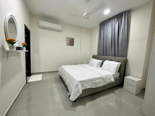 Schlafzimmer mit einem Bett mit weißer Bettwäsche und einem Fenster in der Unterkunft Muscat sand apartments in Muscat