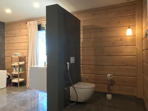 a bathroom with a toilet and a wooden wall at Maison écologique de qualité supérieure in Monflanquin