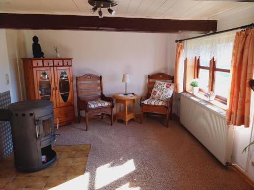 uma sala de estar com cadeiras e um fogão a lenha em Kleines historisches Reetdachhaus auf altem Deich em Helse