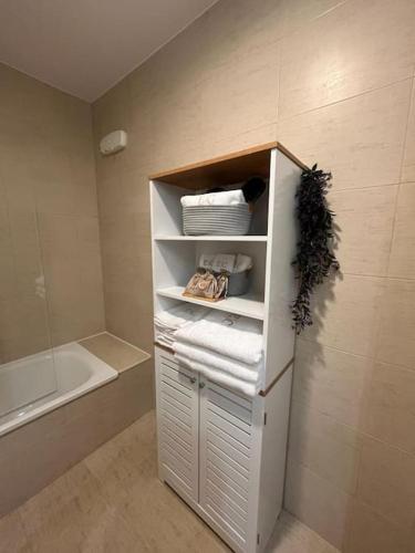 a bathroom with a white cabinet with towels and a tub at Encanto Comillas in Comillas