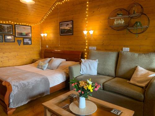 a living room with a bed and a couch at Cherry Cabin - Little Log Cabin in Wales in Bettws Cedewain