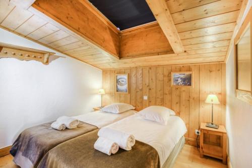 deux lits dans une chambre avec plafonds en bois dans l'établissement Résidence Le Roselend - maeva Home - Appartement 3 Pièces 6 Personnes - Sélection MAE-0980, à Bourg-Saint-Maurice