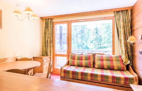 ein Wohnzimmer mit einem Sofa, einem Tisch und einem Fenster in der Unterkunft Les Résidences de Valmorel - maeva Home - 2 Pièces 5 Personnes Confort 79 in Valmorel