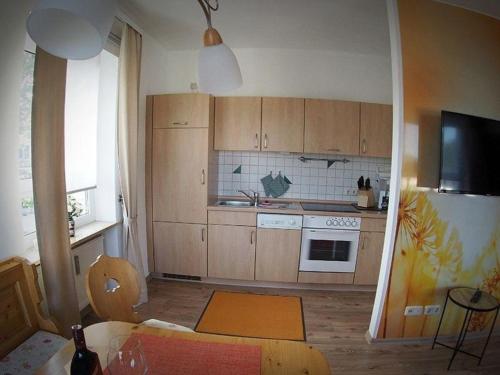 uma pequena cozinha com armários de madeira e uma mesa em Herzlich Willkommen im Vier Jahreszeiten Gäste Apartments Bad Steben em Bad Steben