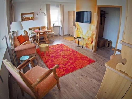 - un salon avec un canapé et un tapis rouge dans l'établissement Herzlich Willkommen im Vier Jahreszeiten Gäste Apartments Bad Steben, à Bad Steben