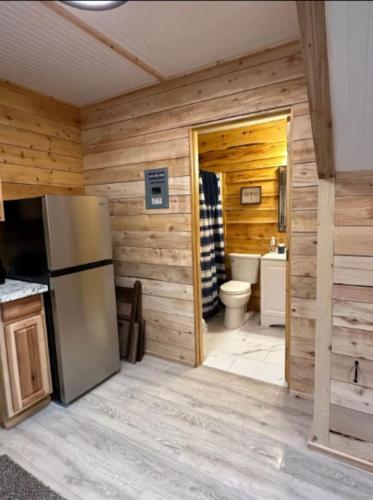 a kitchen with a refrigerator and a bathroom with a toilet at Sockeye Salmon Sanctuary, Cabin 6 at Lower Kenai Lodge in Kenai
