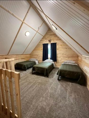a attic room with two green beds and a window at Sockeye Salmon Sanctuary, Cabin 6 at Lower Kenai Lodge in Kenai