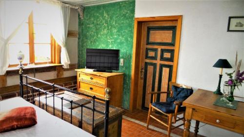 Schlafzimmer mit einem Bett, einem Schreibtisch und einem TV in der Unterkunft Saniertes historisches Fischerhaus Godewind rechte Haushälfte mit Studio in Altwarp