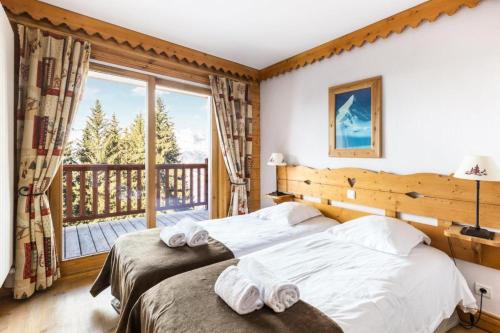 une chambre avec deux lits et un balcon dans l'établissement Résidence Le Roselend - maeva Home - Appartement 4 Pièces 8 Personnes - Sélection MAE-1642, à Bourg-Saint-Maurice