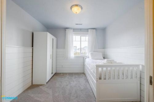 a white bedroom with a crib and a window at Oquirrh Mountain Haven in South Jordan