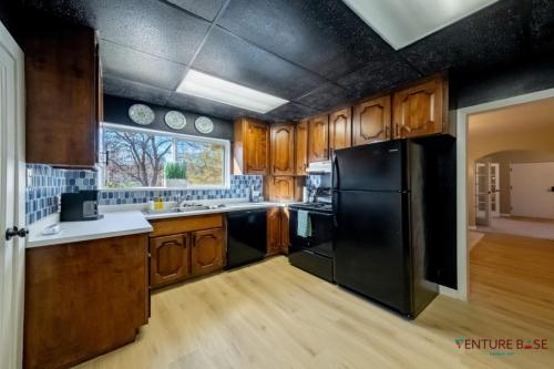 a kitchen with wooden cabinets and a black refrigerator at Wanderlust Hideaway, Venture Base Unit 1 in Kanab