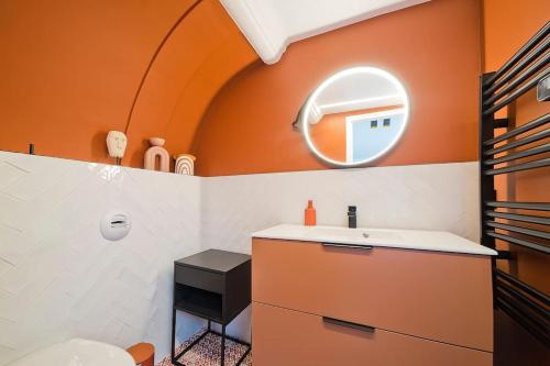 La salle de bains orange est pourvue d'un lavabo et d'un miroir. dans l'établissement Sublime Loft à St Germain (3 chambres), à Paris