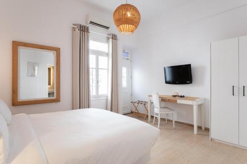 a white bedroom with a white bed and a desk at Spitarona Town House - Largest VIlla in the Center in Mýkonos City