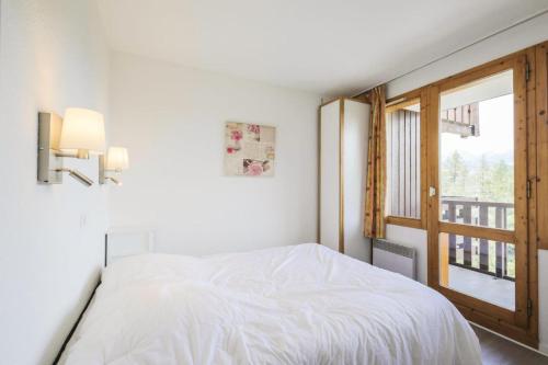 une chambre blanche avec un lit et une fenêtre dans l'établissement Résidence Le Hameau du Sauget - maeva Home - 3 Pièces 6 Personnes Sélection MAE-1979, à La Plagne Tarentaise
