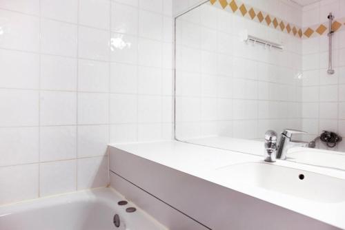 une salle de bain blanche avec une baignoire et un miroir dans l'établissement Quartier Crève Cœur - maeva Home - 2 Pièces 5 Personnes Confort MAE-2007, à Valmorel