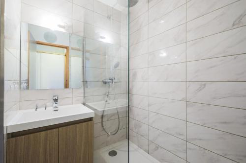 une salle de bain blanche avec un lavabo et une douche dans l'établissement Résidence Le Hameau du Sauget - maeva Home - 3 Pièces 6 Personnes Sélection MAE-1979, à La Plagne Tarentaise