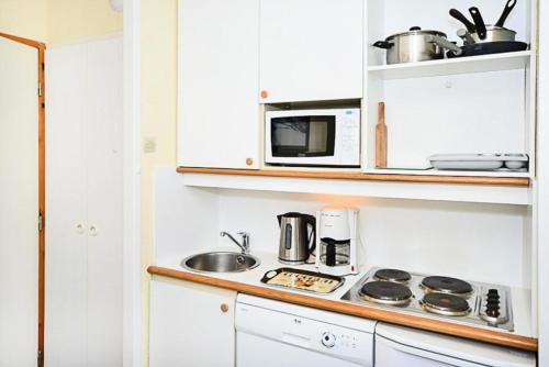 une cuisine avec une cuisinière et un micro-ondes dans l'établissement Résidence Le Hameau du Sauget - maeva Home - Studio 4 Personnes Budget MAE-1981, à La Plagne Tarentaise