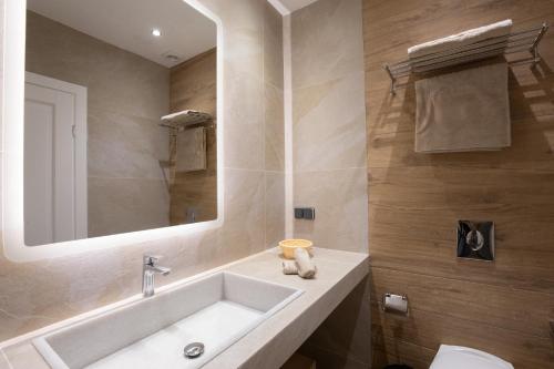 a bathroom with a sink and a mirror and a toilet at Spitarona Town House - Largest VIlla in the Center in Mýkonos City