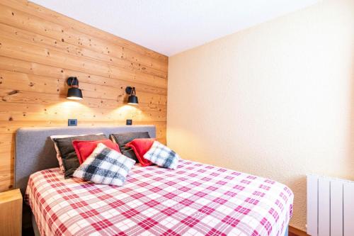 une chambre avec un lit avec des oreillers rouges et noirs dans l'établissement Quartier Crève Cœur - maeva Home - 2 Pièces 5 Personnes Sélection MAE-2001, à Valmorel