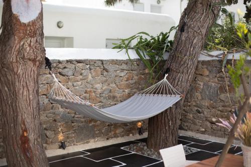 a hammock hanging between two trees next to a stone wall at Spitarona Town House - Largest VIlla in the Center in Mýkonos City