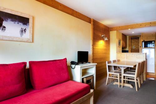 un salon avec un canapé rouge et une table dans l'établissement Résidence Les Néreïdes - maeva Home - 3 Pièces 7 Personnes Sélection MAE-2010, à La Plagne Tarentaise