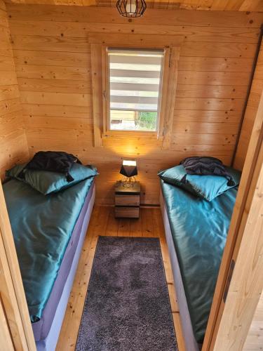 two beds in a log cabin with a window at Domki Letniskowe przy Strażnicy in Wünschelburg
