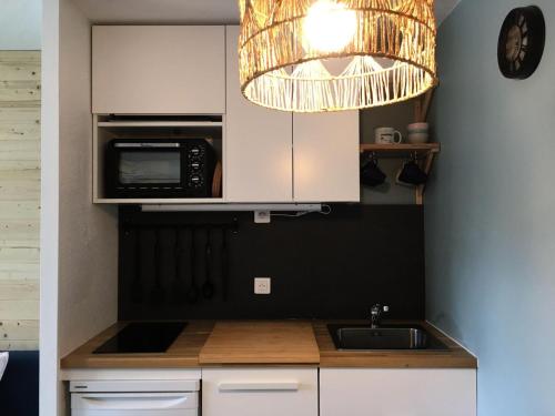 une cuisine avec un micro-ondes et un évier dans l'établissement Résidence Le Cédrat - maeva Home - Appartement 2 pièces 5 personnes au pied des pistes - Prestige - Super Home MAE-3437, à Avoriaz