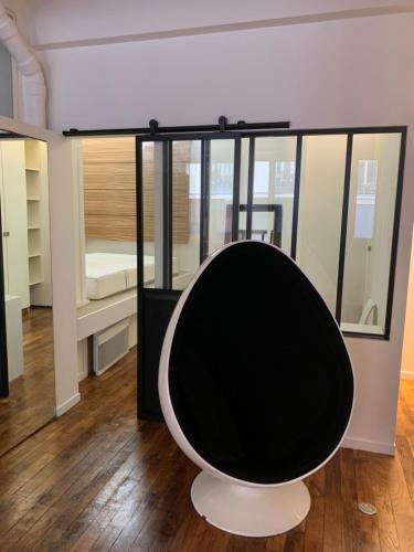 - un fauteuil noir et blanc dans une chambre avec un lit dans l'établissement loft Montmartre au pieds des vignes, à Paris