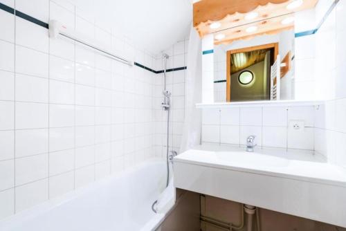 une salle de bain blanche avec un lavabo et un miroir dans l'établissement Quartier Crève Cœur - maeva Home - 2 Pièces 6 Personnes Confort MAE-3620, à Valmorel