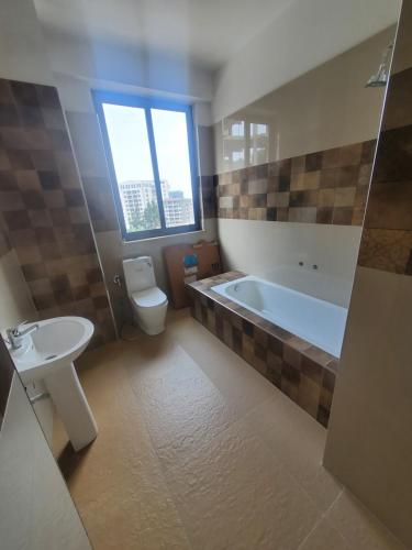 a bathroom with a tub and a toilet and a sink at YOLE Furnished Apartments in Addis Ababa