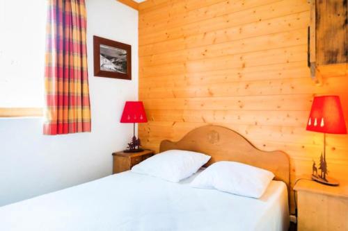 Cet hébergement comprend 2 lits dans une chambre dotée de murs en bois et de 2 lampes. dans l'établissement Résidence Les Sentiers du Tueda - maeva Home - 2 Pièces 4 Personnes Sélection MAE-3511, à Les Allues
