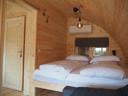 two beds in a wooden cabin with a window at Polderlodge in Hillegom