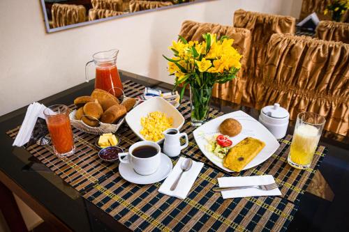 a breakfast table with breakfast foods and coffee and flowers at Hotel Independencia in Huaraz