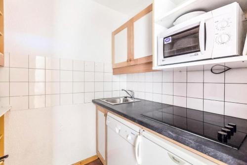 une cuisine avec un évier et un micro-ondes dans l'établissement Quartier Crève Cœur - maeva Home - Duplex 3 Pièces 8 Personnes Confort MAE-3603, à Valmorel
