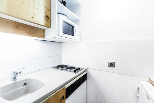 une cuisine blanche avec un évier et un micro-ondes dans l'établissement Quartier Crève Cœur - maeva Home - Studio 4 Personnes - Confort MAE-3612, à Valmorel