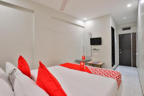 ein Schlafzimmer mit einem roten und weißen Bett mit roten Kissen in der Unterkunft OYO Nova Hotel Nildeep in Rajkot