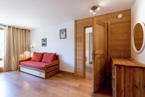 um quarto com um sofá vermelho e uma porta de madeira em Résidence Les Sentiers du Tueda - maeva Home - 3 Pièces 8 Personnes Prestig 84 em Les Allues