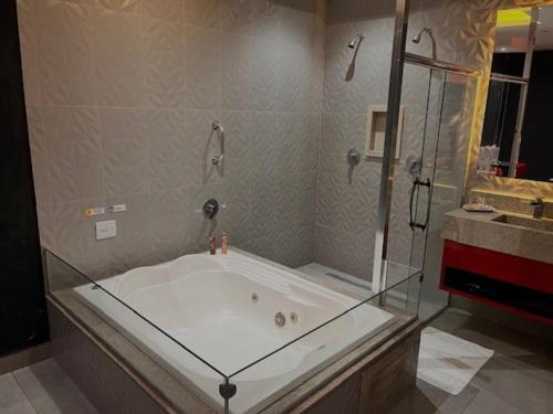 y baño con bañera y ducha acristalada. en Cassino Motel 4, en Santo André