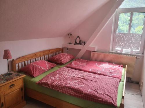 a bedroom with a bed with red sheets and a window at Im Herzen des Elbsandsteingebirges in Königstein an der Elbe