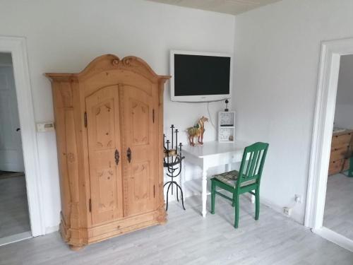 a room with a wooden cabinet and a green chair at Im Herzen des Elbsandsteingebirges in Königstein an der Elbe