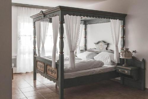 a bedroom with a canopy bed with white sheets at Ferienhaus in Sankt Margarethen Im Lungau mit Garten, Terrasse und Whirlpool in Sankt Margarethen im Lungau