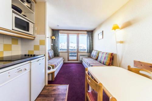Il comprend une petite cuisine et un salon avec un canapé. dans l'établissement Résidence Les Constellations - maeva Home - Studio 4 Personnes - Confort MAE-4505, à La Plagne Tarentaise