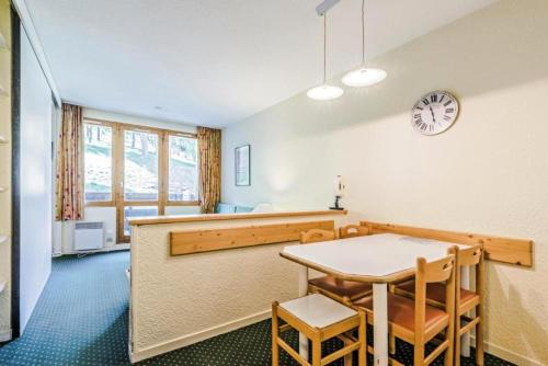 une salle à manger avec une table et une horloge au mur dans l'établissement Résidence Le Hameau du Sauget - maeva Home - 2 Pièces 4 Personnes Confort MAE-6712, à La Plagne Tarentaise