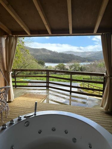 a bath tub in a room with a large window at Cabañas O Recuncho do Sor in O Barqueiro