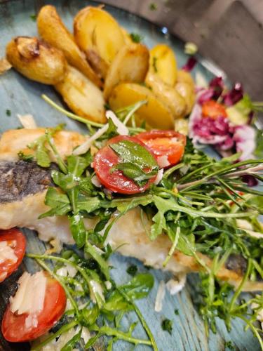 a plate of food with tomatoes and greens on it at Hotel-Restaurant Thüringer Hof in Bad Frankenhausen