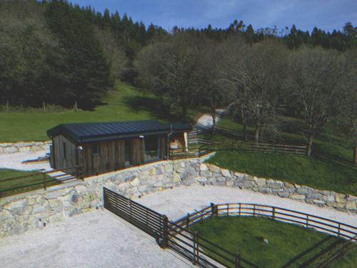 a building with a fence and a stone wall at Cabañas O Recuncho do Sor in O Barqueiro